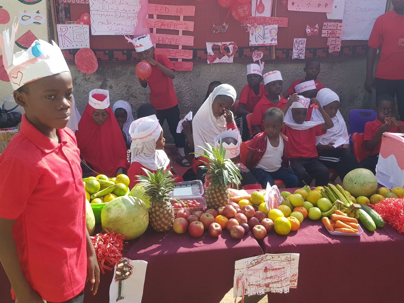 Learners taking part in a red-themed school display with fruits and crafts