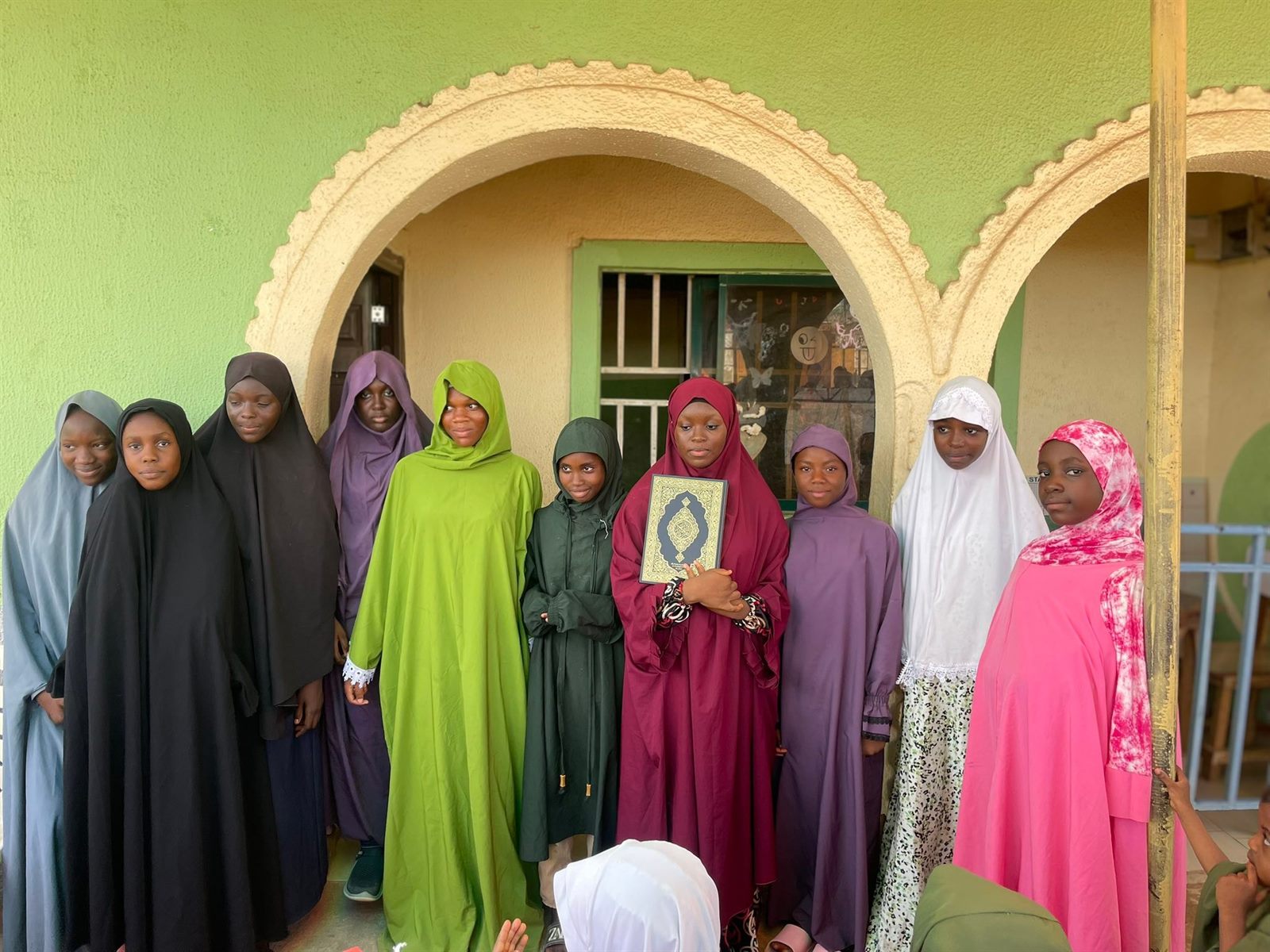 Young learners in white attire during an Islamic learning activity